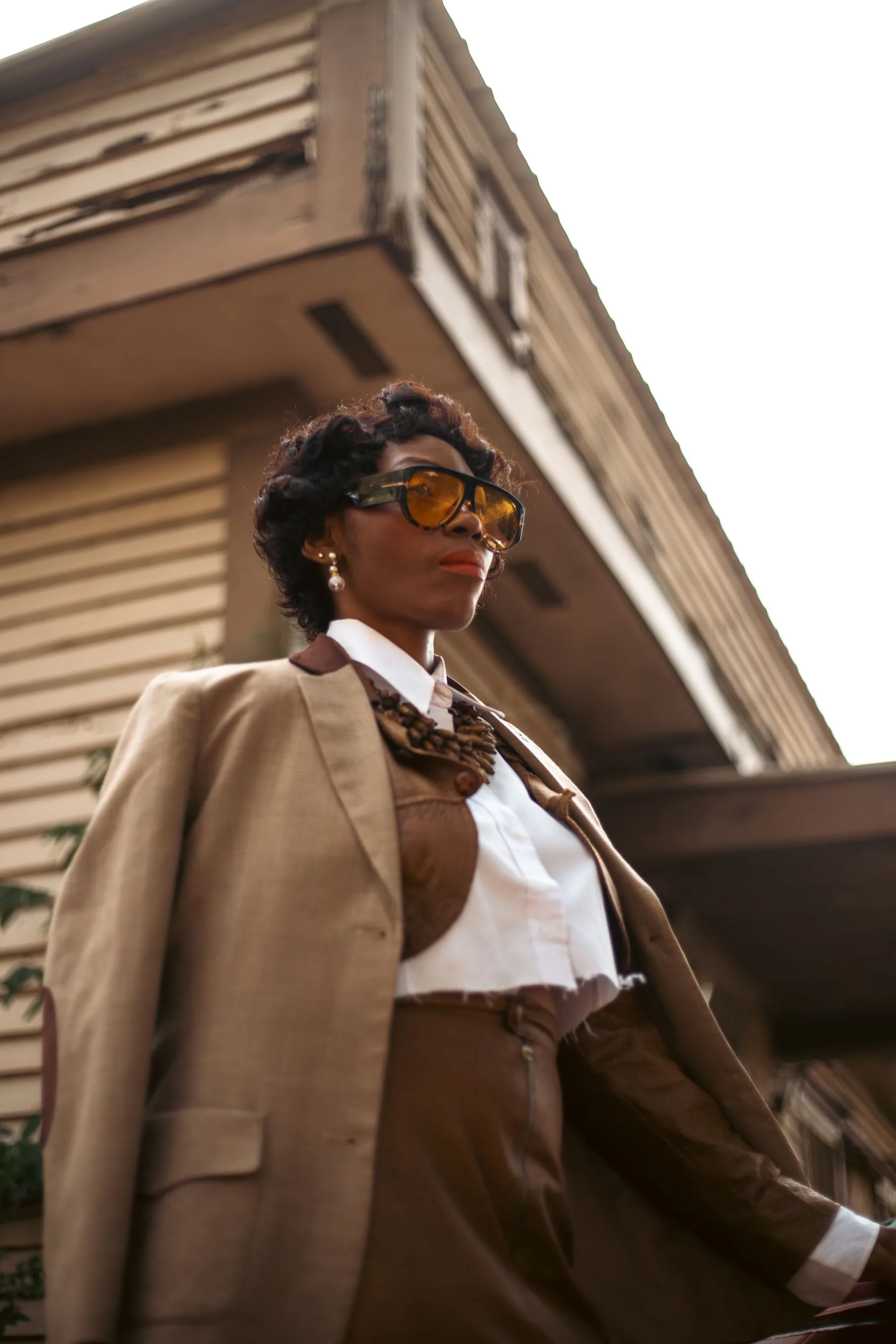 Woman in an earth-toned vintage-inspired suit outside a weathered building