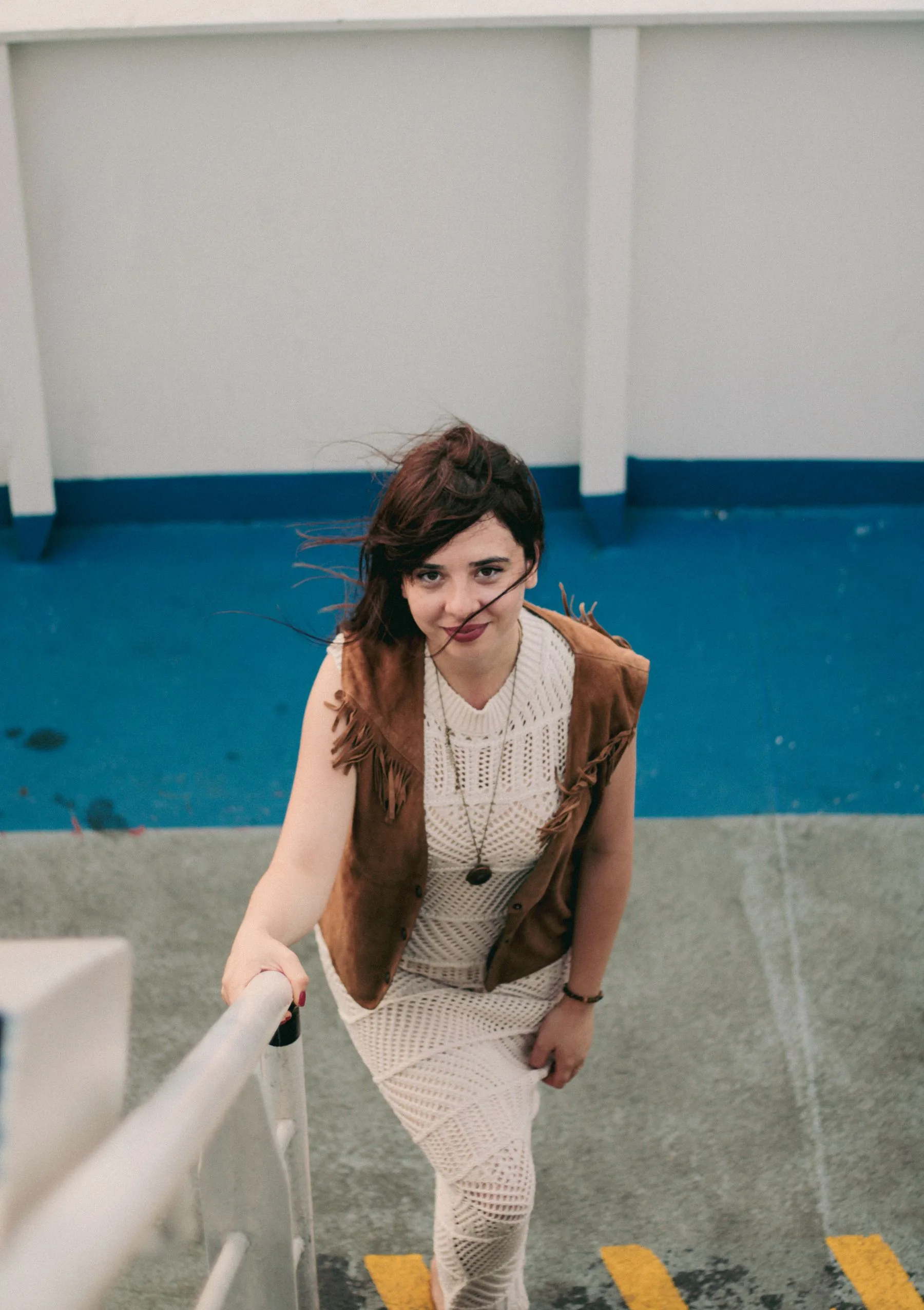 Woman wearing a brown vest over a dress outdoors
